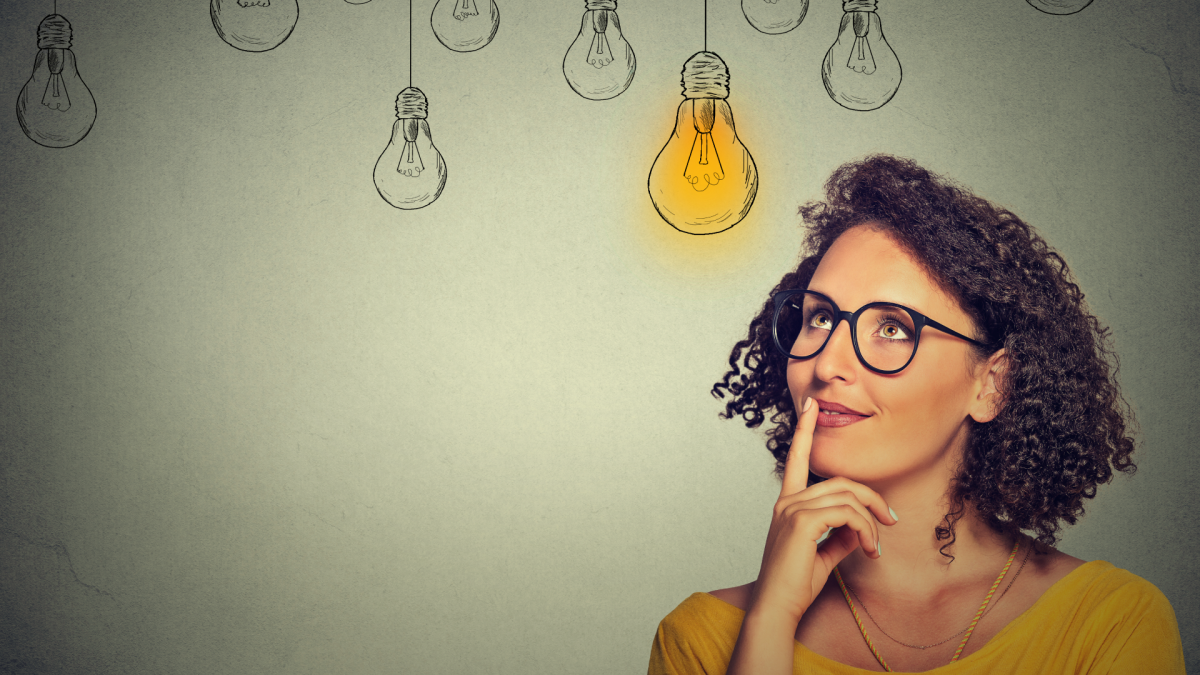 A thinking woman with glasses looks up at drawings of hanging light bulbs that signify ideas.