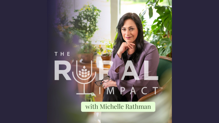 A dark-haired woman with eyeglasses in her hand sits in green chair surrounded by houseplants; white letters are overlaid and read The Rural Impact.