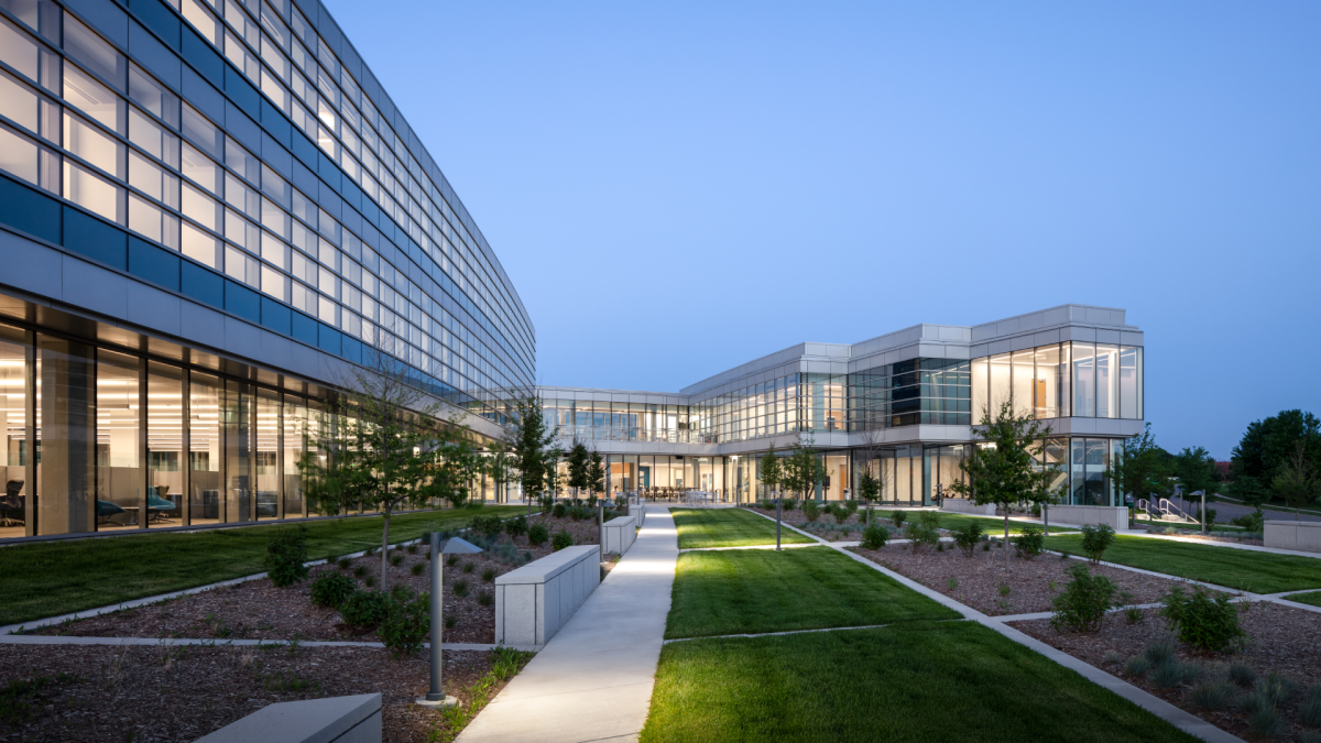 A view of the green grass and glass windows of Ascendium's headquarters at dusk.