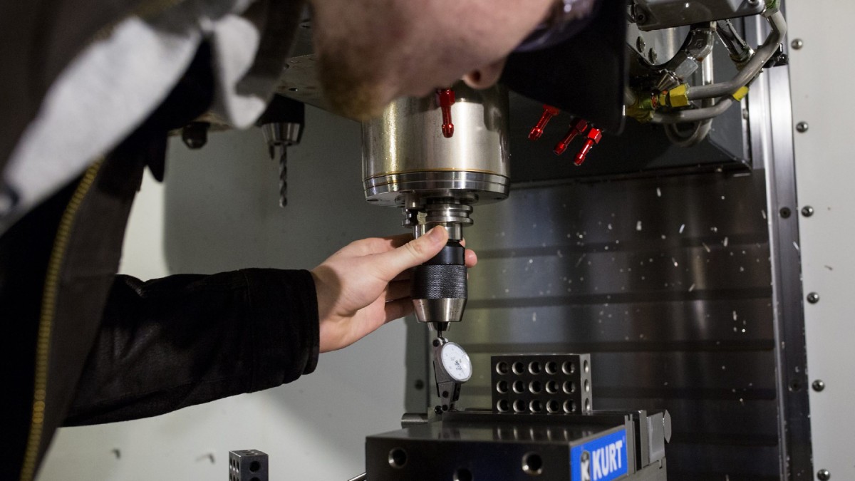 An apprentice wears protective eyewear while operating a tool