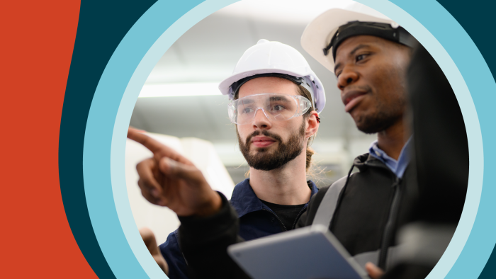 Two men wearing hard hats point at a computer screen enthusiastically