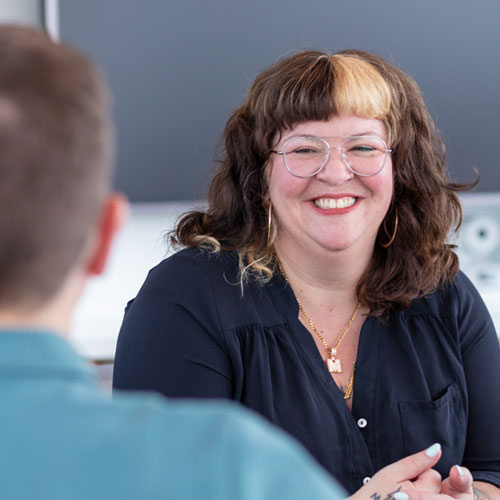 Woman smiling and talking with a fellow employee.